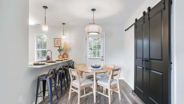 A dining area with a round table, chairs, pendant lights, and a sliding door.