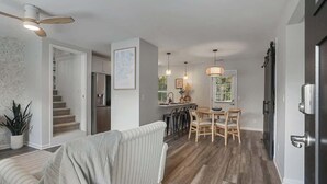 A modern interior with a dining area, kitchen, and a staircase leading to another level.