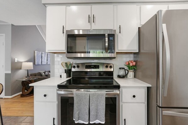 A modern kitchen with white cabinets, a stainless steel microwave, and a built-in oven.