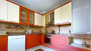 A kitchen with wooden cabinets, a dishwasher, an oven, and a microwave. - Time Traveller's Mansion in Fatih (Istanbul)