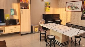 A modern kitchen with a central island, stools, a microwave, a refrigerator, and a piano.