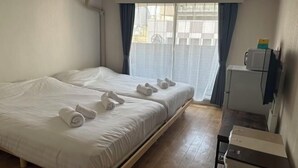 A hotel room with two beds, a small desk, a microwave, and a window with curtains. - DYNAST SHIBUYA NO.1 (Tokyo)