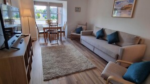 A living room with a sofa, chairs, a coffee table, a TV, and a dining table with chairs. - Bright 1 bedroom Apartment in Drymen (Drymen)