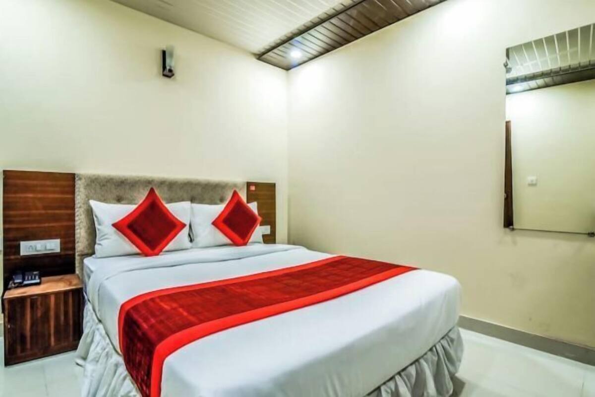 A hotel room with a bed, a nightstand, a mirror, and a ceiling with a wooden panel design.