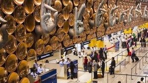 A busy airport check-in area with a unique wall of circular metallic objects and a central counter. - Hotel Swastik Stay (New Delhi)