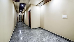A hallway with a marble floor, beige walls, and a ceiling with recessed lighting. - Hotel Swastik Stay (New Delhi)
