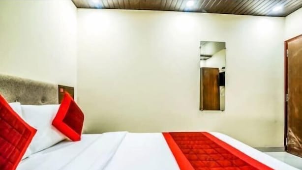 A hotel room with a bed, a mirror, and a door. - Hotel Swastik Stay (New Delhi)