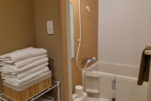 A bathroom with a stack of white towels, a toilet, and a shower area. - TAITO ASAKURA STAY (Tokyo)