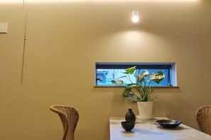 A dining area with a table, chairs, a vase, and a window with a view. - TAITO ASAKURA STAY (Tokyo)