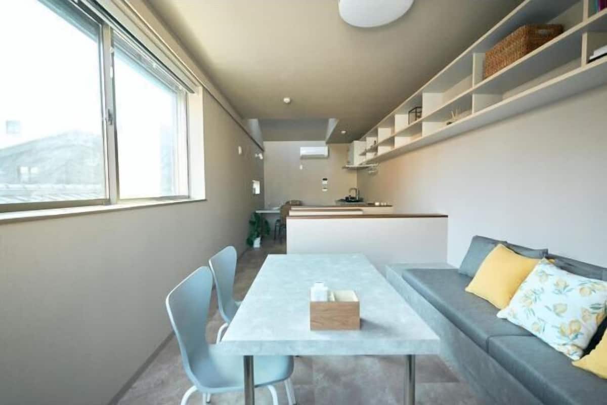A modern interior with a dining table, chairs, a sofa, and a kitchen area.