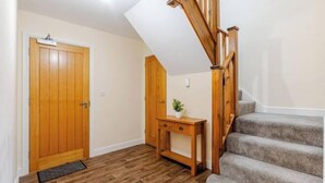 A staircase with wooden railings, a wooden door, and a small wooden console table with a plant. - Cosy Modern Flat, Cockermouth, Sleeps 4 (Cockermouth)