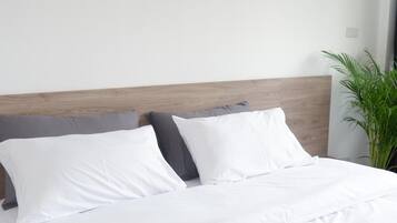 Ein ordentlich bezogenes Bett mit weißen Leinentextilien und einem Holzkopfende.