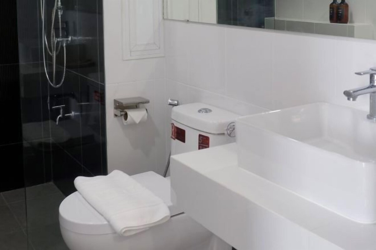 A modern bathroom with a white toilet, a large white sink, and a glass shower enclosure.