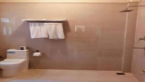 A bathroom with a toilet, a shower, and a towel rack. - Courtyard Pujan Hotel - Thamel (Kathmandu)