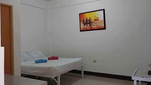 Una stanza con un letto, un tavolino e un quadro appeso al muro.