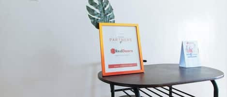 A small table with a framed sign, a potted plant, and a small stand with a card.