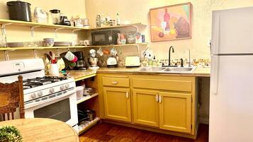 Una cocina con estufa, horno, microondas, lavamanos y armarios amarillos.