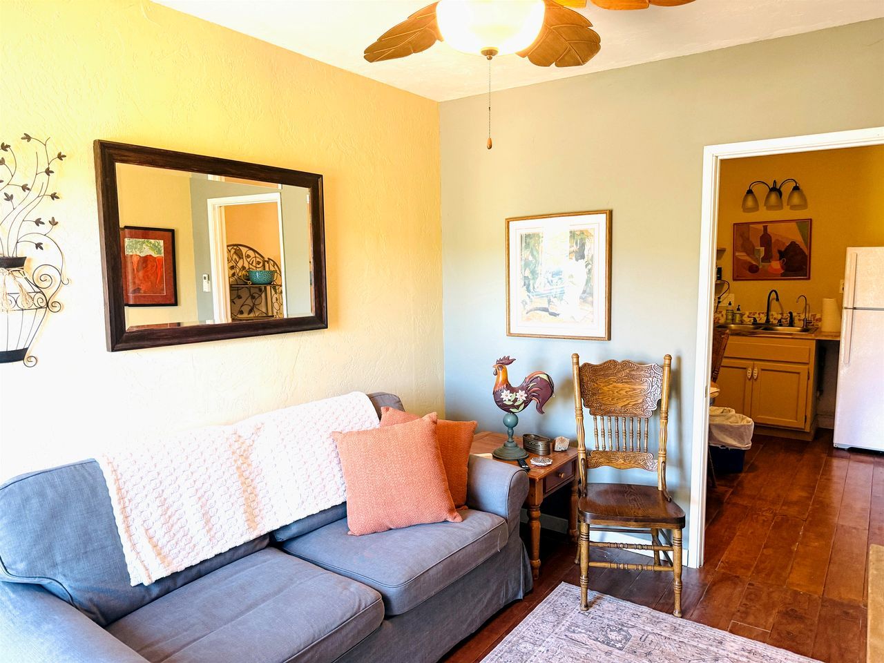 A living room with a sofa, a chair, a table, and a ceiling fan.