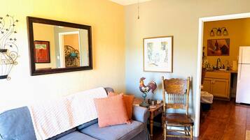 A living room with a sofa, a chair, a table, and a ceiling fan.