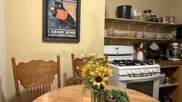 A kitchen with a stove, oven, and various kitchenware on shelves.
