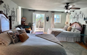 A bedroom with two beds, a ceiling fan, and a view of the outdoors.