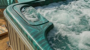A hot tub with a wooden deck, surrounded by Adirondack chairs, set against a backdrop of trees and mountains. - Pet Friendly Breathtaking Cottage with Hot-tub in Rainbow, California (Fallbrook)