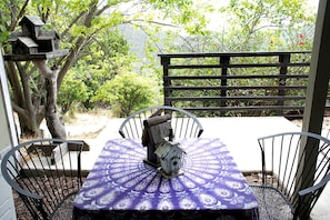 A patio with a table and chairs, surrounded by a wooden fence and trees.