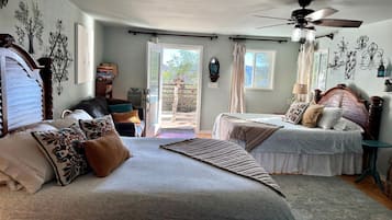 A bedroom with two beds, a ceiling fan, and a view of the outdoors.