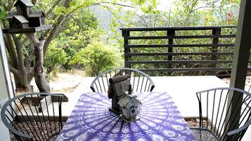 A patio with a table and chairs, surrounded by a wooden fence and trees.