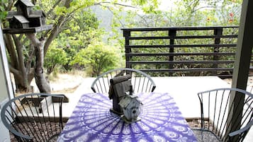 A patio with a table and chairs, surrounded by a wooden fence and trees.