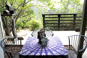 A patio with a table and chairs, surrounded by a wooden fence and trees.