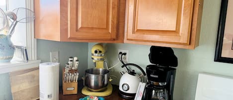 A kitchen with wooden cabinets, a mixer, a kettle, and a coffee maker.