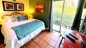 Un dormitorio con cama, un escritorio con silla, una ventana con cortinas y un aire acondicionado instalado en la pared.
