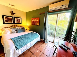 A bedroom with a bed, a desk with a chair, a window with curtains, and a wall-mounted air conditioner. - Pet Friendly Breathtaking Cottage with Great Views and Hot-tub in Rainbow, California (Fallbrook)