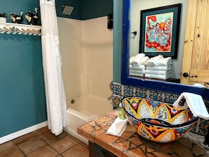 Une salle de bain équipée d’une douche, d’une baignoire, d’un lavabo avec un récipient coloré et d’un porte-serviettes.