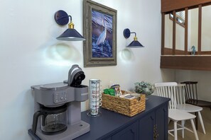 A coffee station with a coffee maker, a mug holder, and a decorative basket. - SEA GLASS COTTAGE, OCEAN VIEWS, BEACH ACCESS 1 MINUTE AWAY, HANDICAP FRIENDLY! (Avalon)