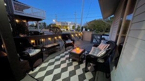 Een terras met tuinmeubilair, een geruite vloer en lichtslingers.