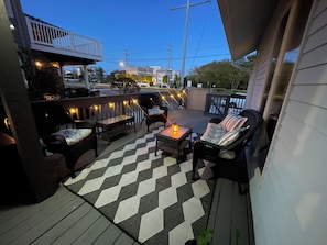 A deck with outdoor furniture, a checkered floor, and string lights.