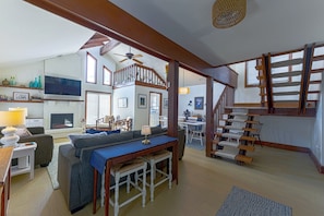 Un vaste espace de vie doté d’une cheminée, d’une table à manger et d’un escalier avec des rampes en bois.