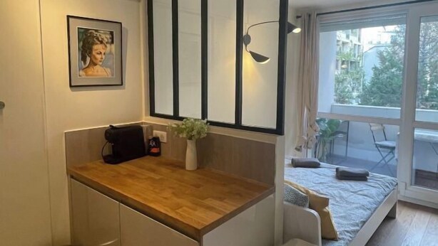 A modern bedroom with a bed, a small desk, a chair, a window with a view of the outside, and a wall-mounted light fixture. - Studio 650m to Trocadéro Tour Eiffel (Paris)