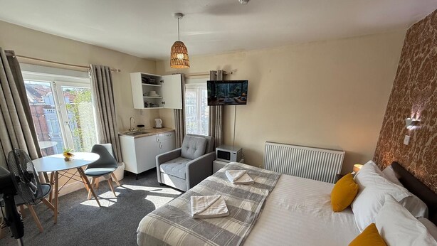 A hotel room with a bed, a desk, a chair, a television, and a window. - Studio 32-Free Private Parking (Portsmouth)