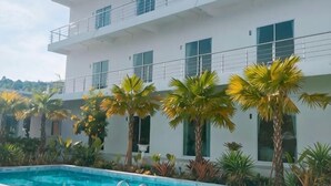 A modern building with a swimming pool, surrounded by palm trees. - Sichon Residence (Sichon)
