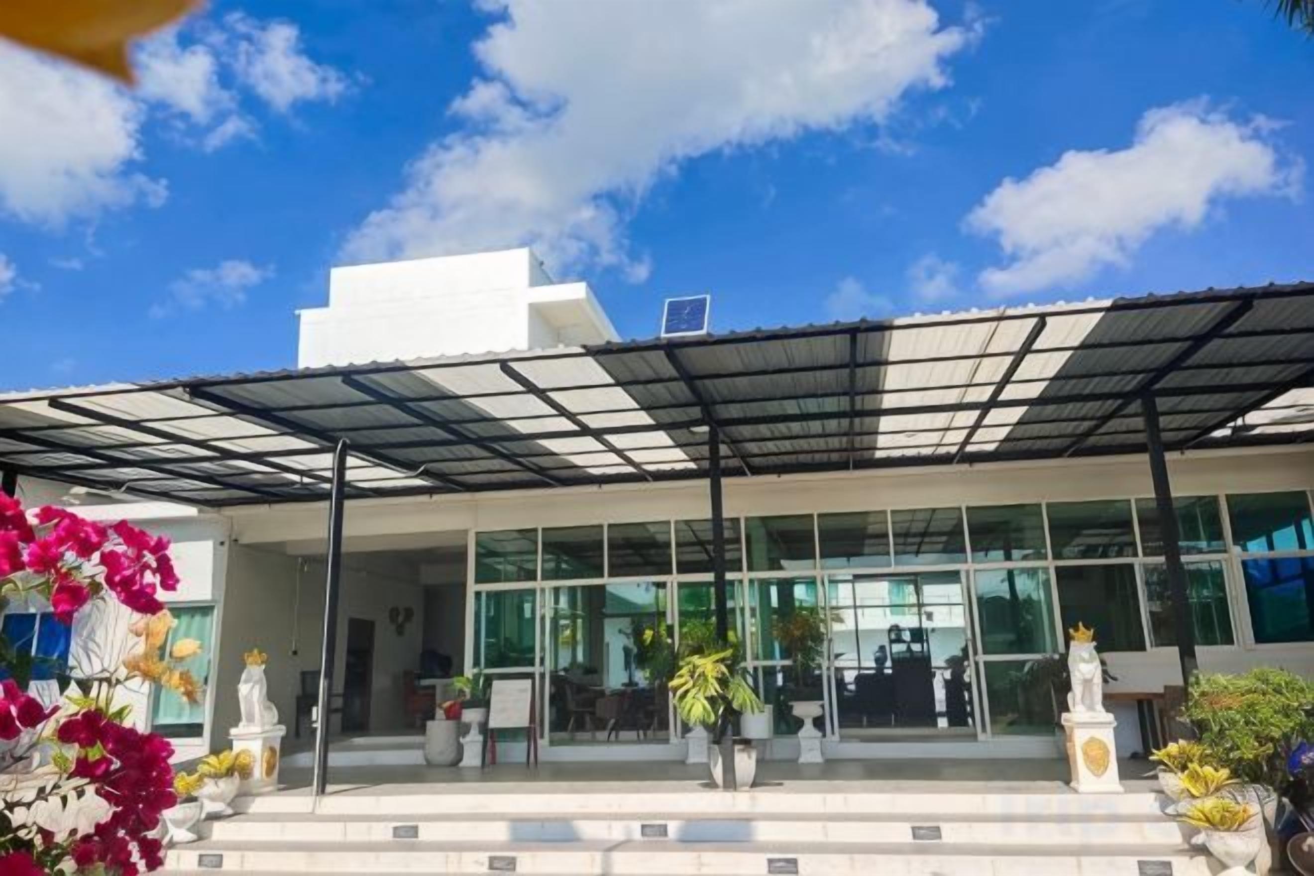 A modern building with a covered entrance, large windows, and outdoor seating area.