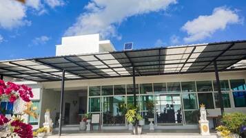 A modern building with a covered entrance, large windows, and outdoor seating area.