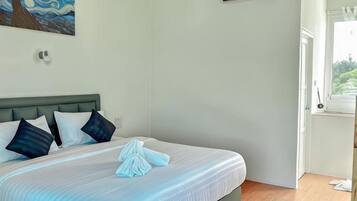 Ein Hotelzimmer mit Bett, Kissen, einem Gemälde und einem Fenster.