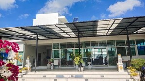 A modern building with a glass facade, a covered entrance, and outdoor seating. - Sichon Residence (Sichon)