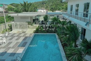 A rooftop pool with a checkered floor, surrounded by palm trees and a view of a building. - Sichon Residence (Sichon)