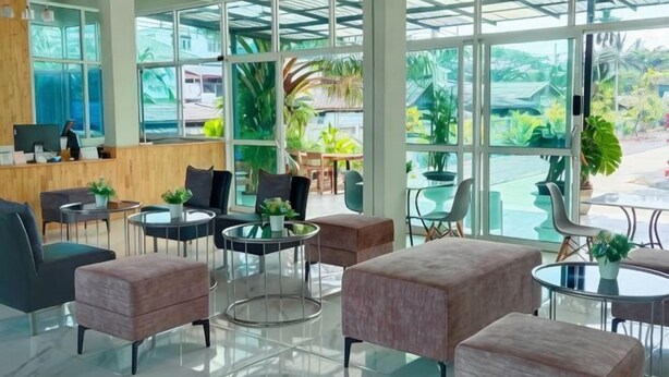 A spacious lobby with a reception desk, seating area, and large windows offering a view of the outdoors. - Sichon Residence (Sichon)