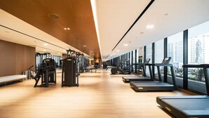 A modern gym with cardio machines, weight stations, and a bench area.