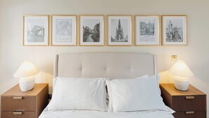 A bedroom with a bed, two nightstands, and five framed pictures on the wall. - Charming Central Mews Home with Secure Parking (Edinburgh)